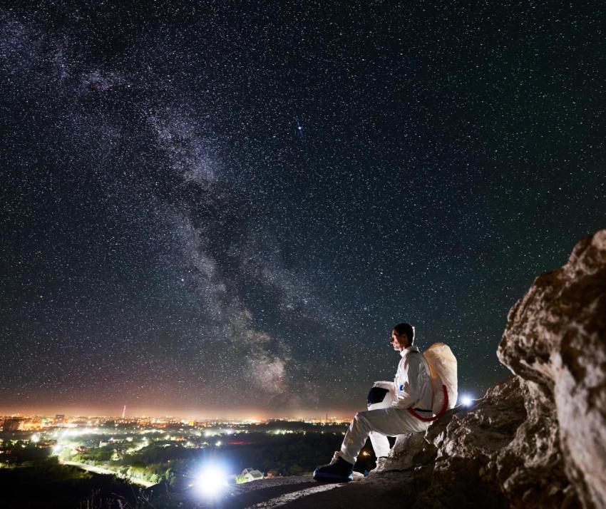 Astronaut sitting on rocky hill under beautiful ni 2023 11 27 04 57 12 utc