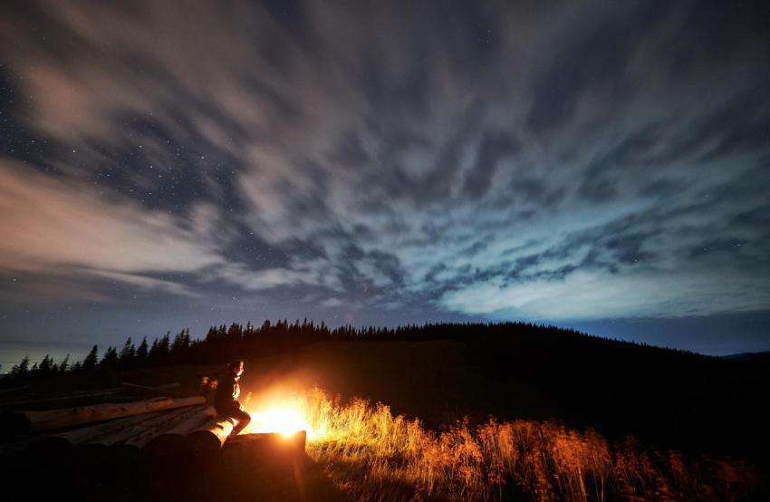 Young man relaxing near bonfire in mountains 2023 11 27 05 08 21 utc