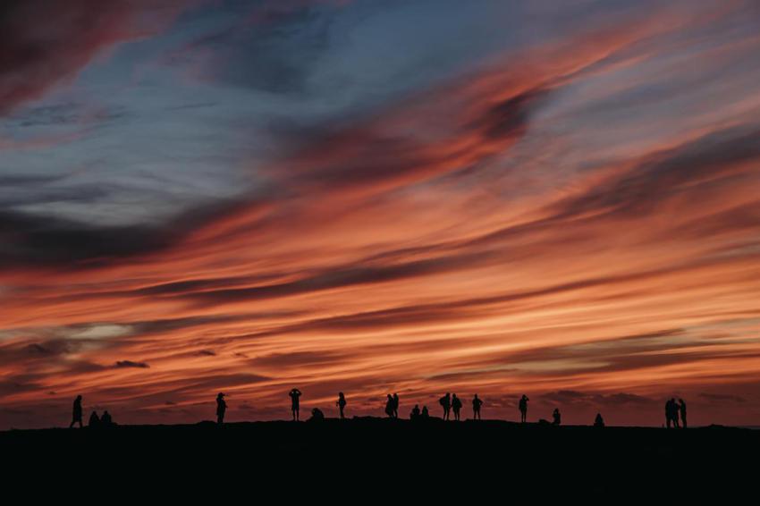 Several people look at the reddish sky at sunset 2023 11 27 05 28 19 utc