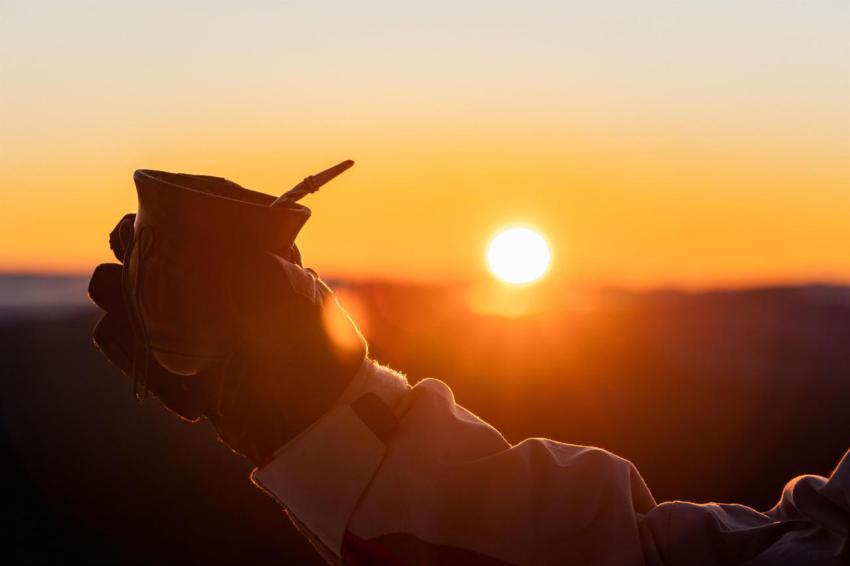 Hand holding a cup against sunset view with a gold 2023 11 27 05 10 46 utc