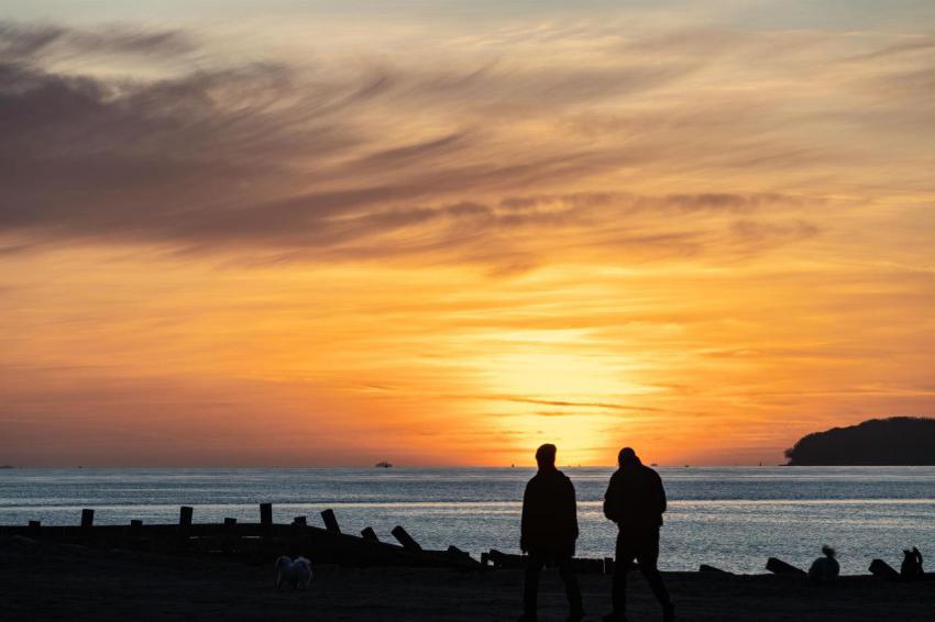 A silhouette of two people standing at the lepe be 2023 11 27 05 20 43 utc