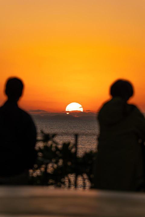 Silhouettes of two people watching a bright orange 2023 11 27 05 09 51 utc
